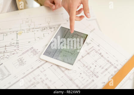 Top view of architect reviewing blueprints and using a digital tablet. Close-up. Stock Photo