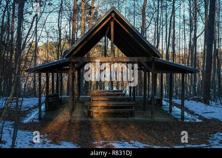 The fading light peeks at an outdoor classroom nestled in the woods with the remnants of snow on the ground at Yates Mill County Park in Raleigh. Stock Photo