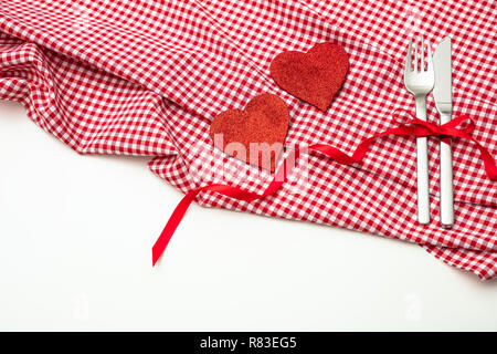 Valentines day dinner, table, place setting. Red hearts on  red checkered table cloth, white background, copy space, top view. Stock Photo