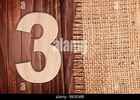 Wooden digit one symbol - 3. On wooden table background wih burlap Stock Photo