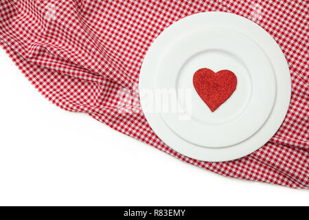 Valentines day dinner, table, place setting. Red heart on white plates, red checkered table cloth, white background, copy space, top view. Stock Photo