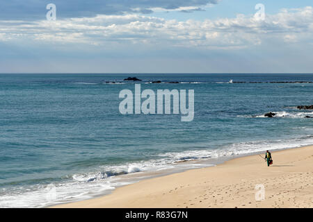 Vila do Conde; Portugal: March 19; 2015: Early spring on a portuguese northern beach with beautiful blue sea and sky, seeing a fisherman walking on th Stock Photo