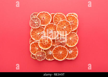 Dried citrus slices lemons & oranges on coral pink colored background. Homemade Christmas natural decoration. Square shape, Flat Lay. Stock Photo