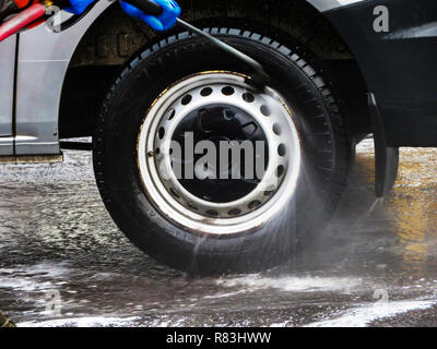 Closeup of man using a Jet Spray to wash a vehicle's wheels in Rotherham, South Yorkshire, England Stock Photo
