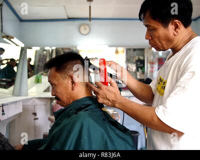ANTIPOLO CITY, PHILIPPINES - DECEMBER 11, 2018: A barber cuts the hair of his customer inside his barbershop. Stock Photo