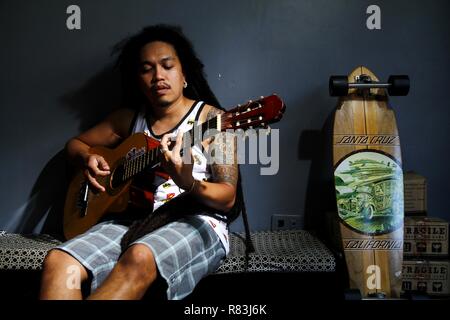 ANTIPOLO CITY, PHILIPPINES - DECEMBER 10, 2018: A Filipino musician plays music using an acoustic guitar. Stock Photo