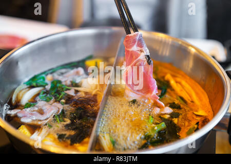 sliced pork meat in hot shabu or sukiyaki or Japanese hot pot Stock Photo