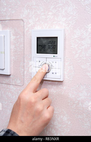 A male hand adjusting the room temperature in winter. Stock Photo