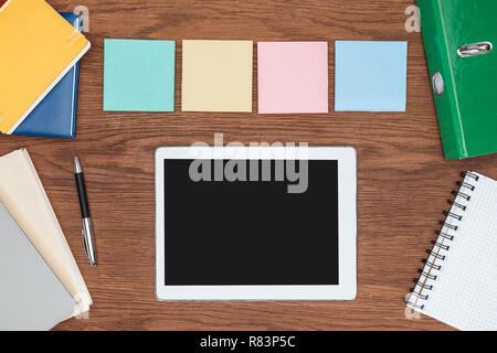 top view of four sticky notes and digital tablet with blank screen on wooden office desk Stock Photo
