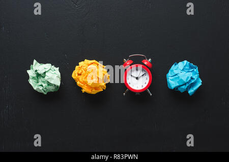 top view of colorful crumpled paper balls and clock on black background, time management concept Stock Photo