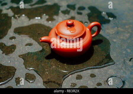 Brewing tea in chinese way (gon fu) with clay pot on surface covered by raindrops Stock Photo