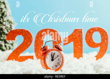 big red 2019 numbers with vintage alarm clock standing on snow on blue background with "it is christmas time" lettering Stock Photo