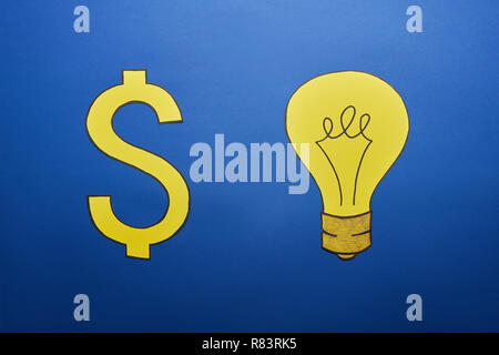 top view of yellow paper light bulb and dollar sign on blue background Stock Photo