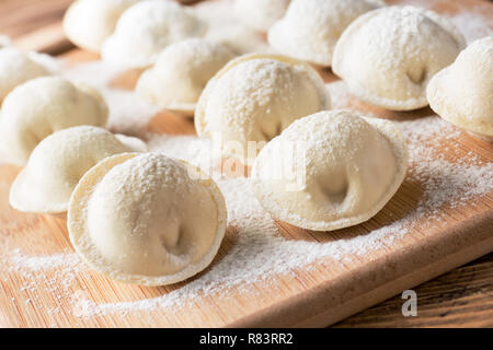 Raw dumplings on a wooden chopping Board in the kitchen. Stock Photo