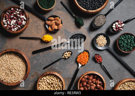 top view of wooden bowls and spoons with superfoods, legumes and grains on table Stock Photo