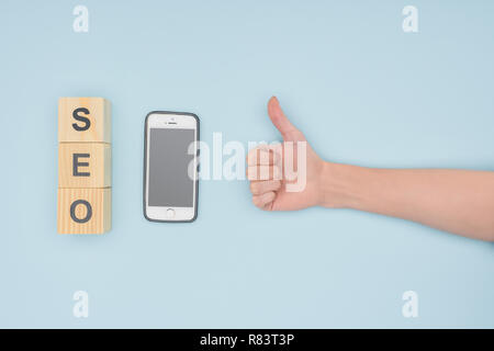 Top view of female seo manager putting thumbs up on light blue background Stock Photo