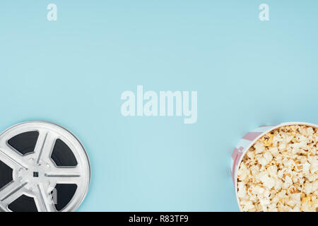 top view of film reel and popcorn in bucket isolated on blue Stock Photo