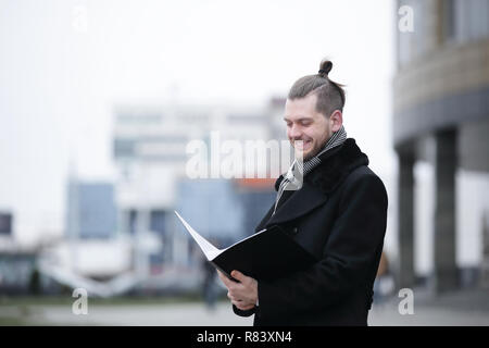 businessman reading documents standing on a city street. Stock Photo