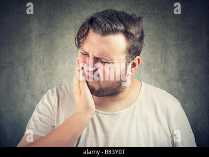 Adult casual man frowning from pain in tooth looking sick and unhappy Stock Photo