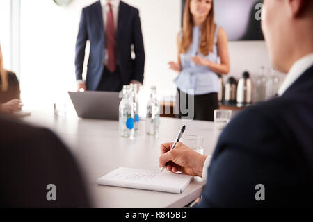 Businessman Making Notes At Group Meeting Around Table On Graduate Recruitment Assessment Day Stock Photo