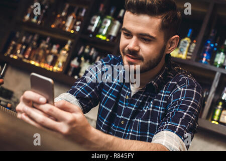 Young bartender leaning on bar counter browsing internet joyful close-up Stock Photo