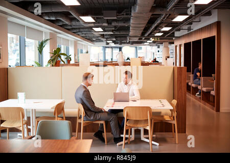 Young Businessman Having Informal Interview In Cafeteria Area At Graduate Recruitment Assessment Day Stock Photo