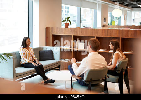 Businessman And Businesswoman Interviewing Female Candidate In Office At Graduate Recruitment Assessment Day Stock Photo