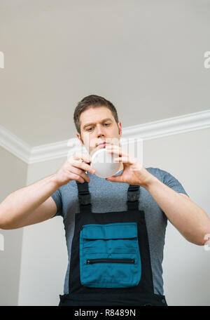 Man checking battery in smoke detector. House maintenance. Stock Photo