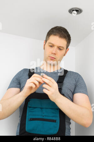 Certified electrician checking burned out light bulb. Stock Photo