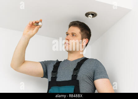 Certified electrician checking burned out light bulb. Stock Photo