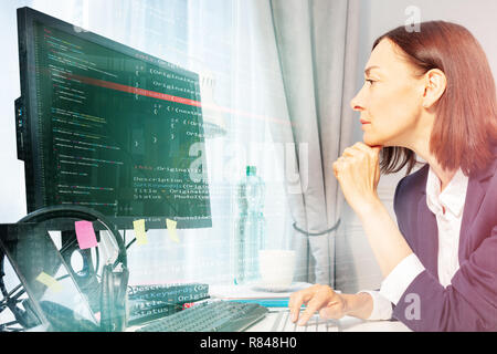 Side view portrait of businesswoman using computer while sitting at the desk in her office Stock Photo
