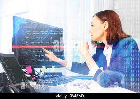 Side view portrait of businesswoman pointing to the screen of computer with her finger while working in the office Stock Photo
