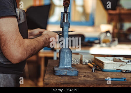 Man works in carpentry workshop. He fixes wooden handle in vice. Different tools are on workbench. Men at work. Hand work. Stock Photo