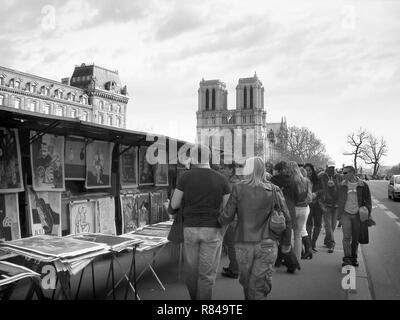 Left bank bouquinistes attract a crowd of young purchasers, Quai Saint-Michel: overseen by Cathedrale Notre Dame, Paris, France. Black and white version Stock Photo