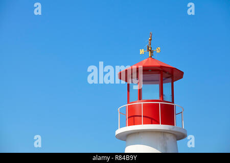 Red top of a lighthouse against the blue cloudless sky. Stock Photo