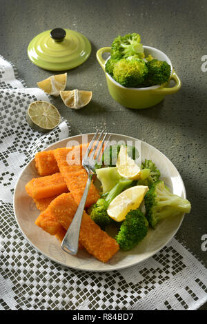 fish sticks with broccoli and lemon garnish - closeup Stock Photo