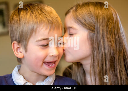 Nine year old girl kissing her seven year old brother on his birthday.  (MR) Stock Photo