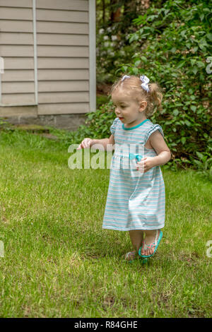 Issaquah, Washington, USA.  18 month old girl having fun exploring a backyard.  (MR) Stock Photo