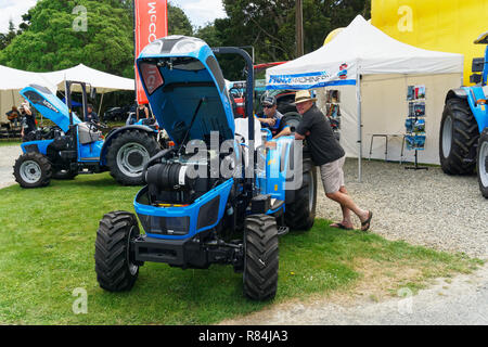 Men leaning on a tractor at an agricultural show in New Zealand Stock Photo