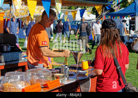 Girl buying mini pancakes at a Dutch food stall, at an open air market in New Zealand Stock Photo