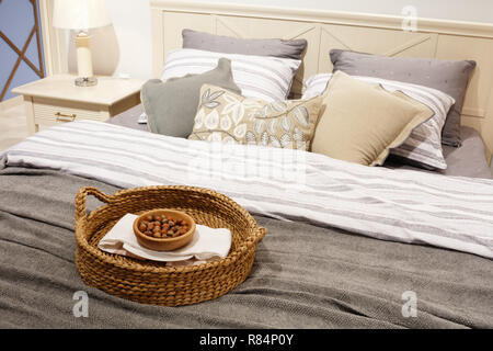 Nuts in a wicker basket on the bed, a gift for guests. luxury modern style bedroom in gray and blue tones, Interior of a hotel bedroom, cushions with  Stock Photo