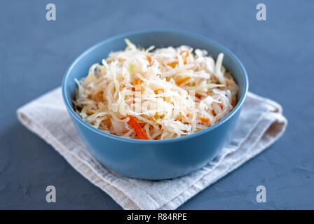 Ceramic bowl of tasty fermented cabbage standing on wooden tabletop Stock Photo