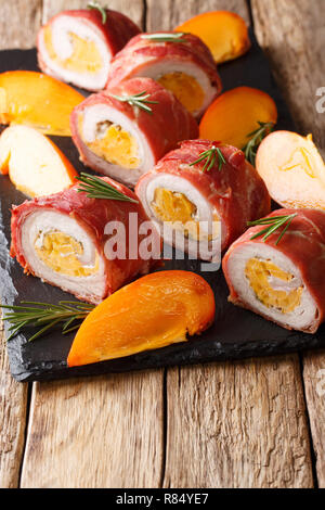 Pork tenderloin baked in prosciutto and stuffed with persimmon and cheese close-up on the table. vertical Stock Photo