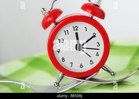 Forks holding alarm clock on plate - Time to eat concept Stock Photo
