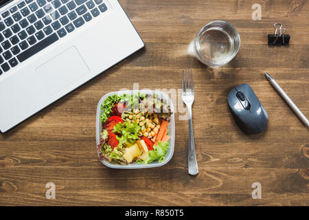 Healthy business lunch in office, salad, water on wooden table. Concept healthy nutrition. Lunchbox. Stock Photo