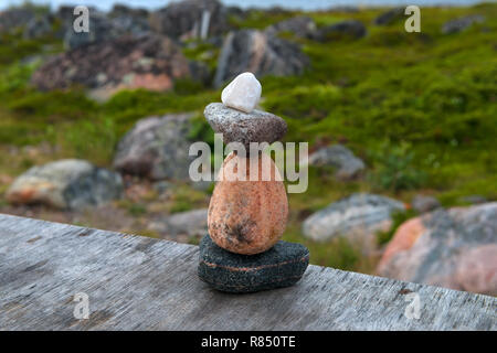 Pyramid of sea stones on the shore of the White Sea at sunset Stock Photo
