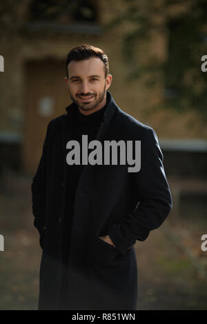 handsome smiling man in black coat Stock Photo