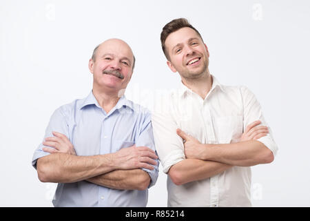 Confident male colleagues keep arms folded, thinks about new project, belong to different age group Stock Photo