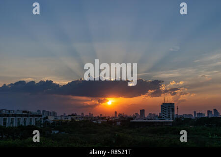 Sunbeam through the dramatic cloud during sunset time, with silhouette building in background Stock Photo