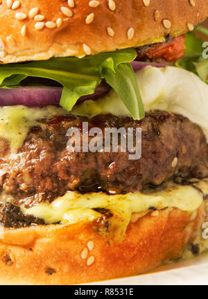 Classic burger in a bun with melting cheese and sauces on a table Stock Photo